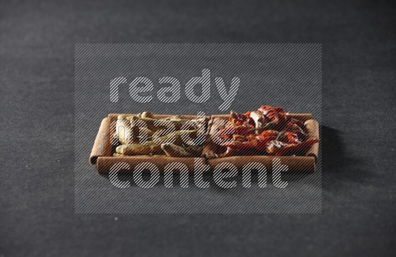 2 squares of cinnamon sticks full of chilis and turmeric fingers on black flooring