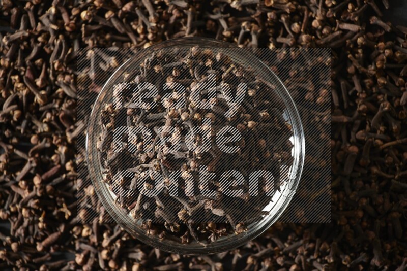 A glass bowl full of cloves on a black flooring