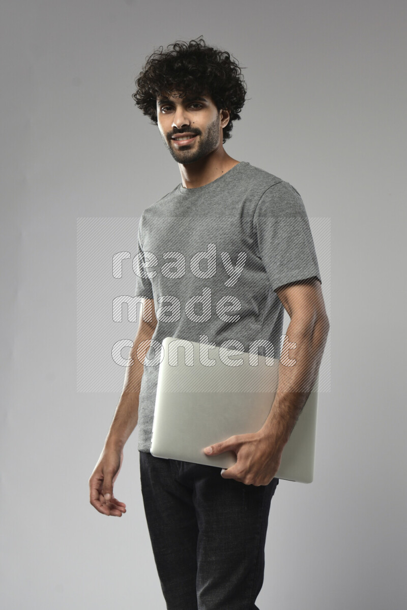 A man wearing casual standing and holding a laptop on white background