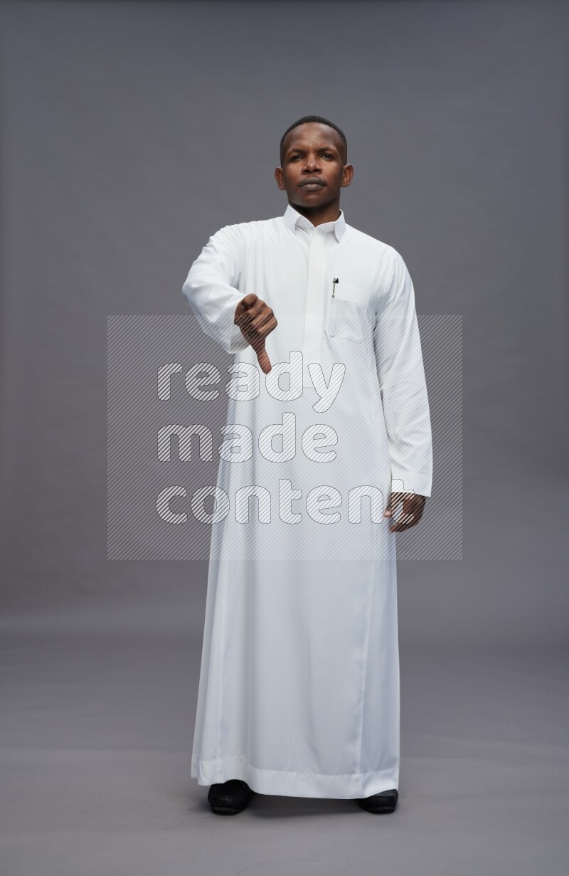 Saudi man wearing thob standing interacting with the camera on gray background