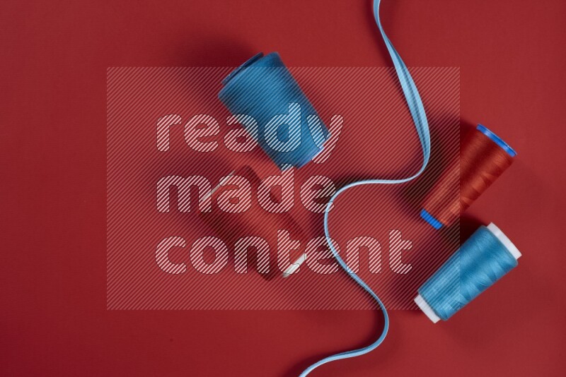 A blue and red collection of sewing and tailoring tools arranged on a red background