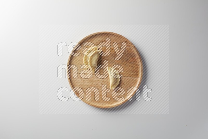 Three Sambosas on a wooden round plate on a white background