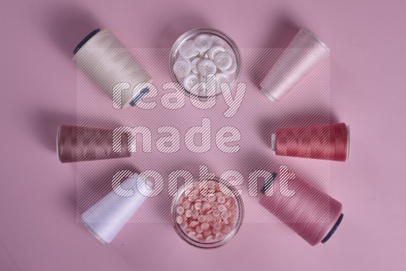A white and pink collection of sewing and tailoring tools arranged on a pink background