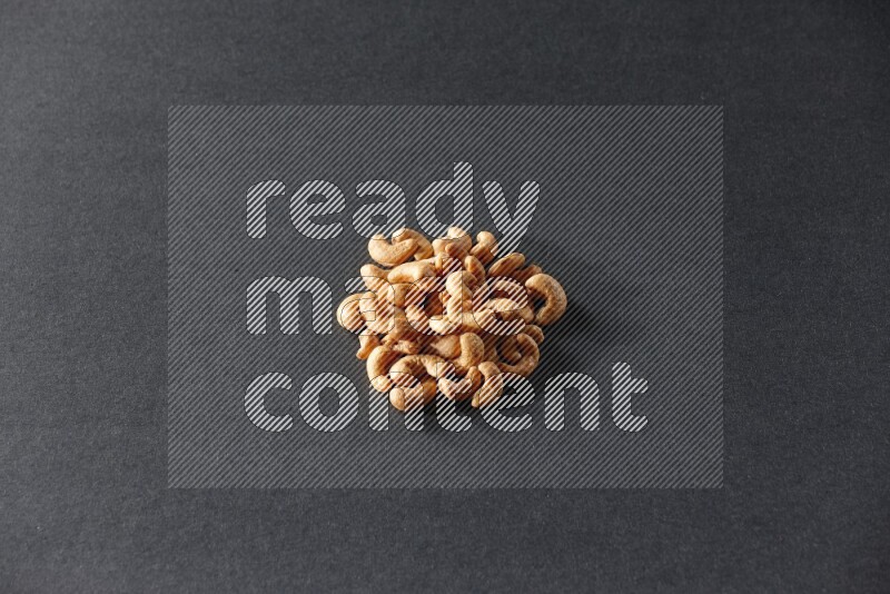 A bunch of cashews on a black background in different angles