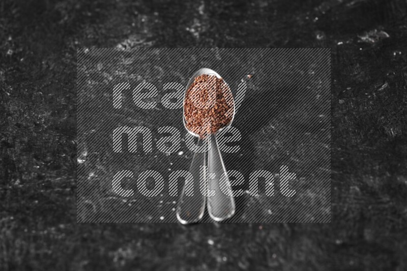 ملعقتان معدنيتان ممتلئتان ببذور حب الرشاد علي خلفية سوداء