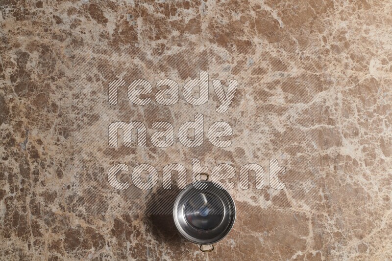 A small copper pot on beige marble background