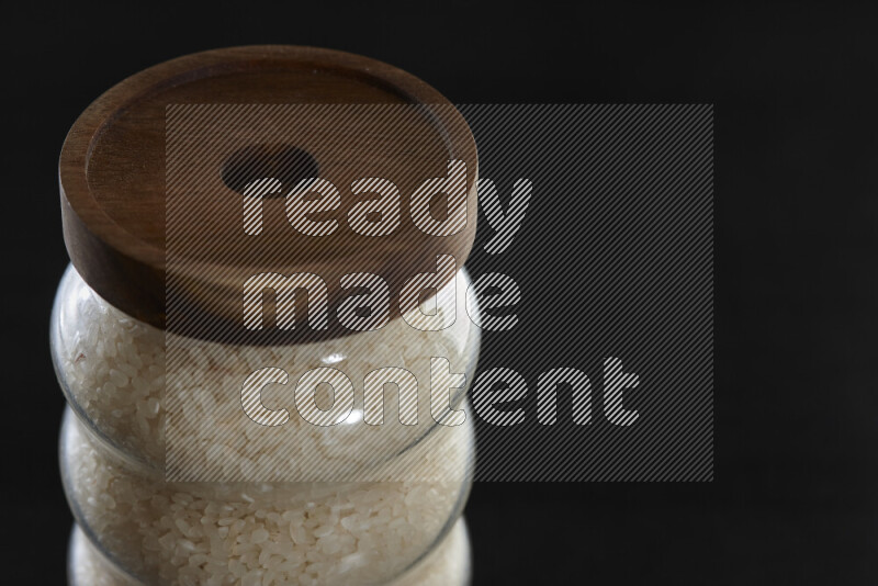 White rice in a glass jar on black background