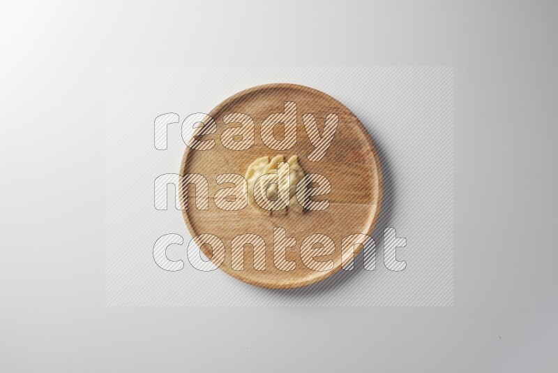 Three Sambosas on a wooden round plate on a white background