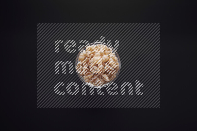 معكرونة قواقع في وعاء زجاجي علي خلفية سوداء