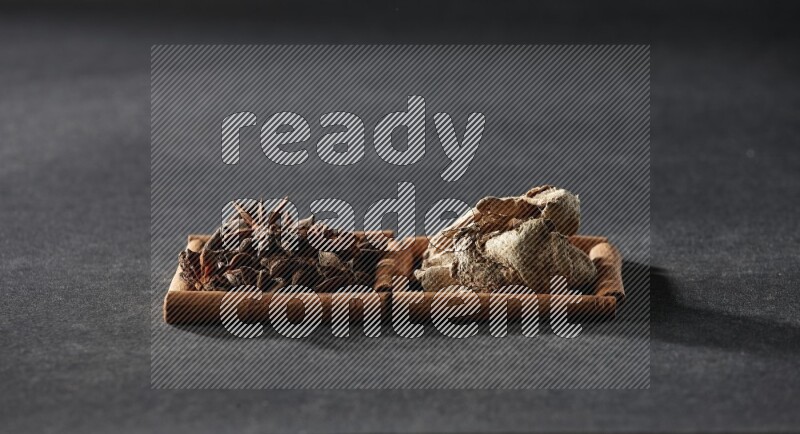 2 squares of cinnamon sticks full of star anise and dried ginger on black flooring