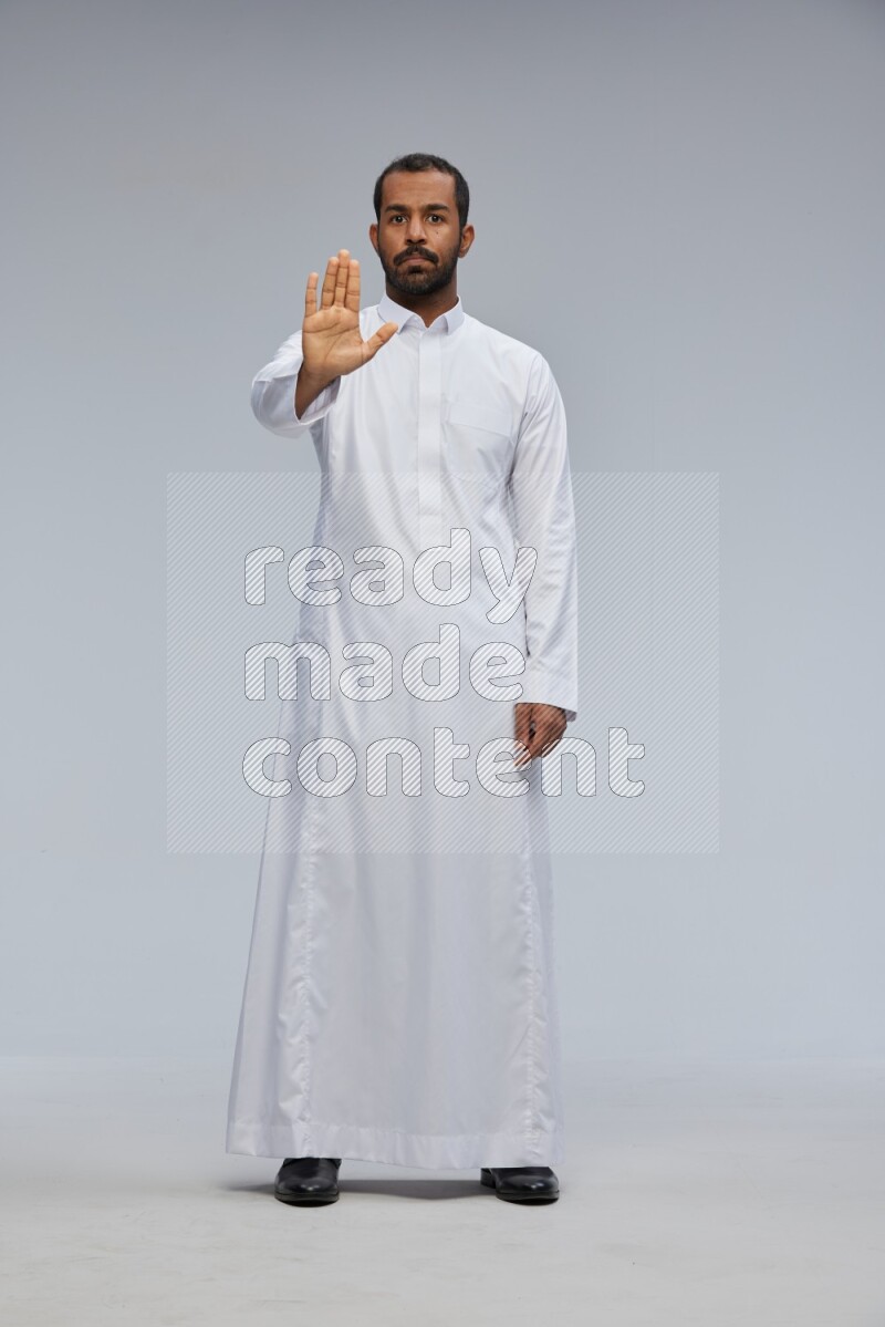Saudi man Wearing Thob standing interacting with the camera on Gray background