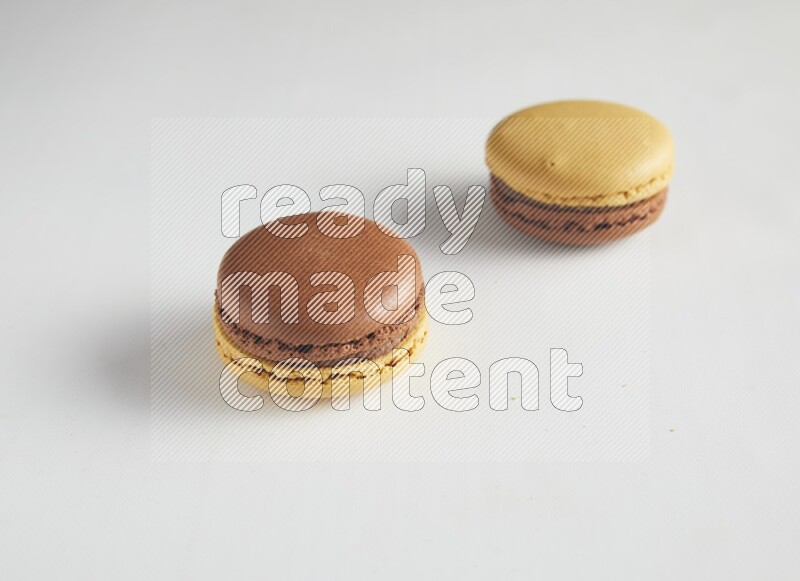 45º Shot of two Yellow and Brown Chai Latte macarons on white background