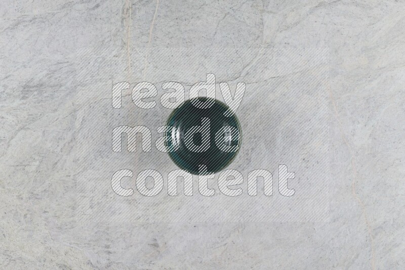 A dark green pottery bowl on grey marble background