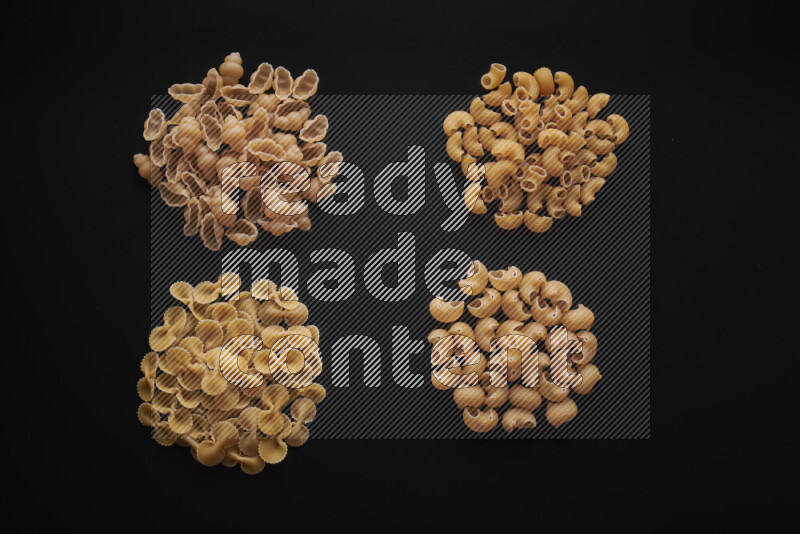 Different pasta types in bunches on black background