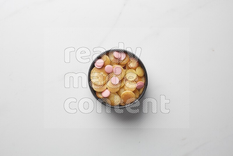 Top-view shot of pink chocolate chips cereal pancakes in a round bowl on white background