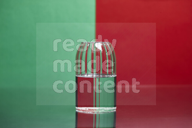 The image features a clear glassware filled with water, set against green and red background
