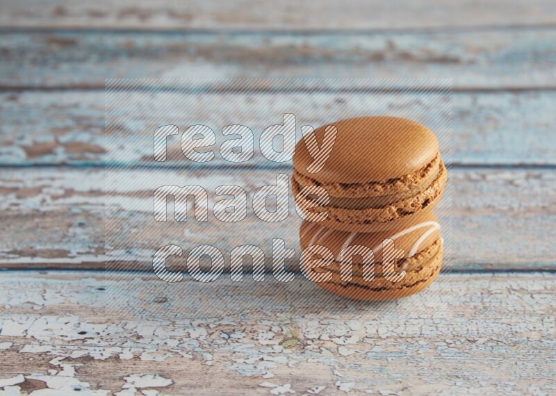 45º Shot of of two assorted Brown Irish Cream, and Brown Maple Taffy macarons  on light blue background