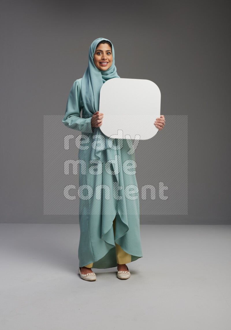 Saudi Woman wearing Abaya standing holding social media sign on Gray background