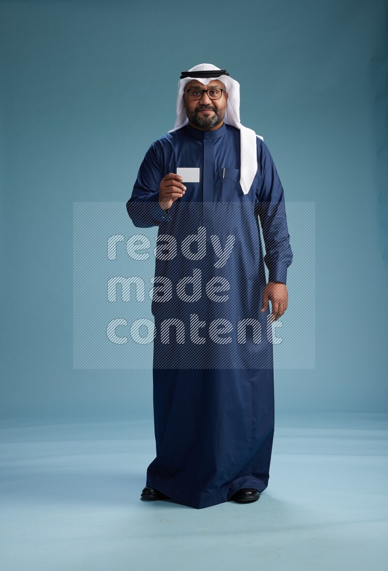 Saudi Man with shimag Standing holding ATM on blue background