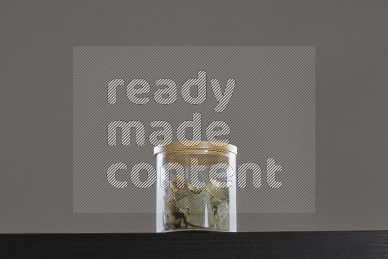 Bay laurel leaves in a glass jar on black background