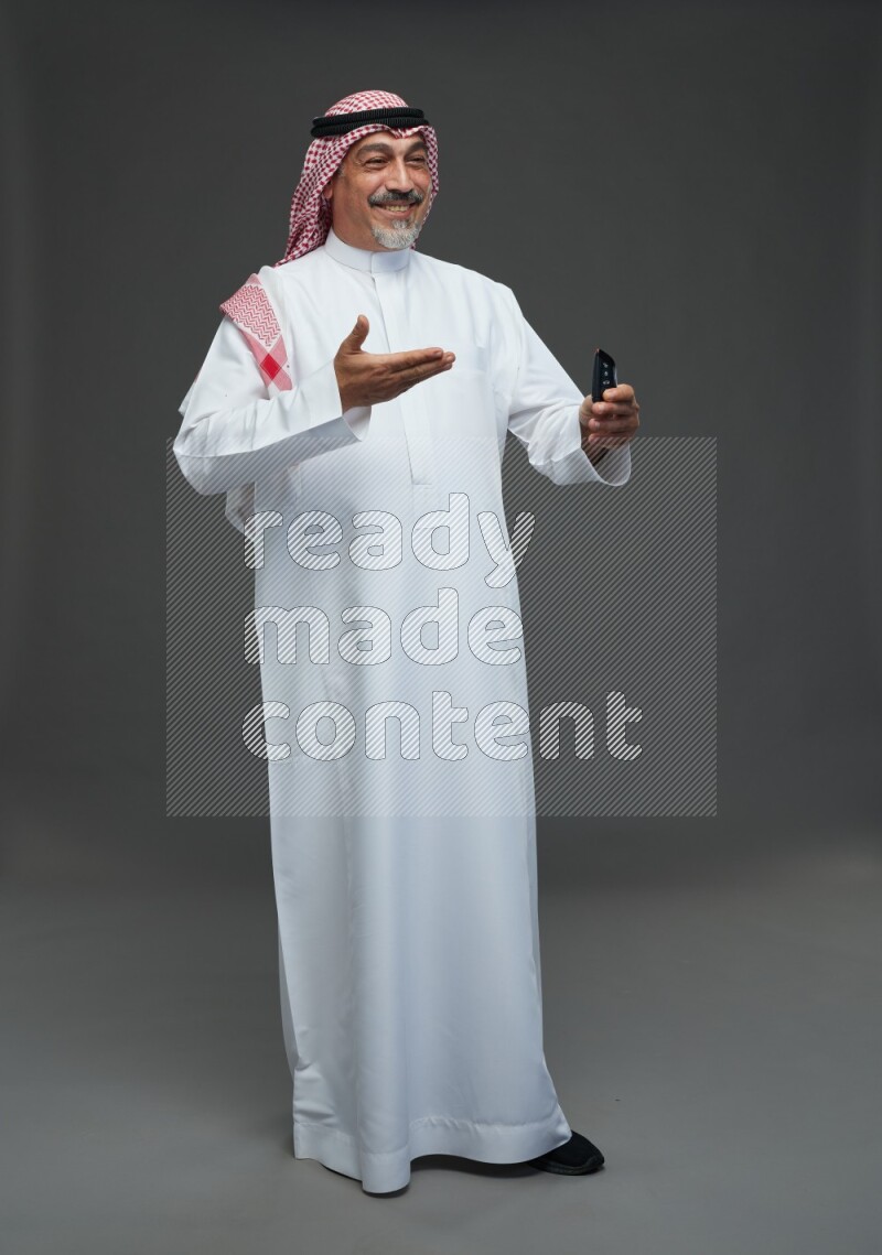 Saudi man with shomag Standing holding car key on gray background