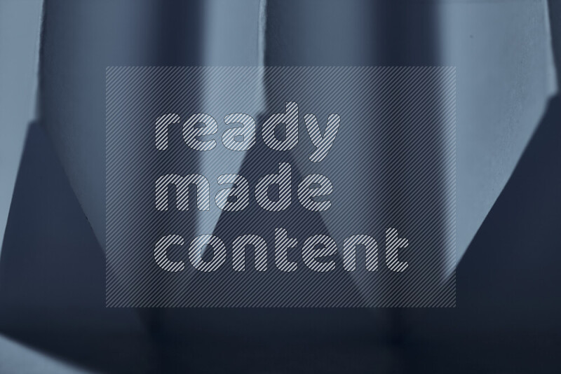 A close-up abstract image showing sharp geometric paper folds in blue gradients