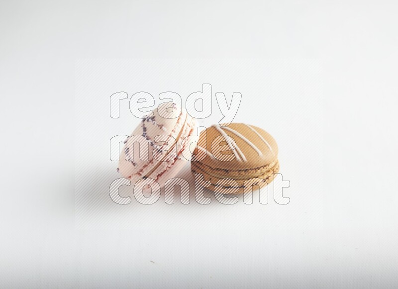 45º Shot of of two assorted Brown Irish Cream, and pink orange blossom macarons on white background