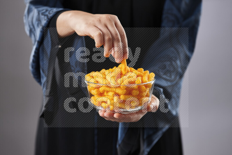 Woman in abaya holding different kinds of snacks in different positions