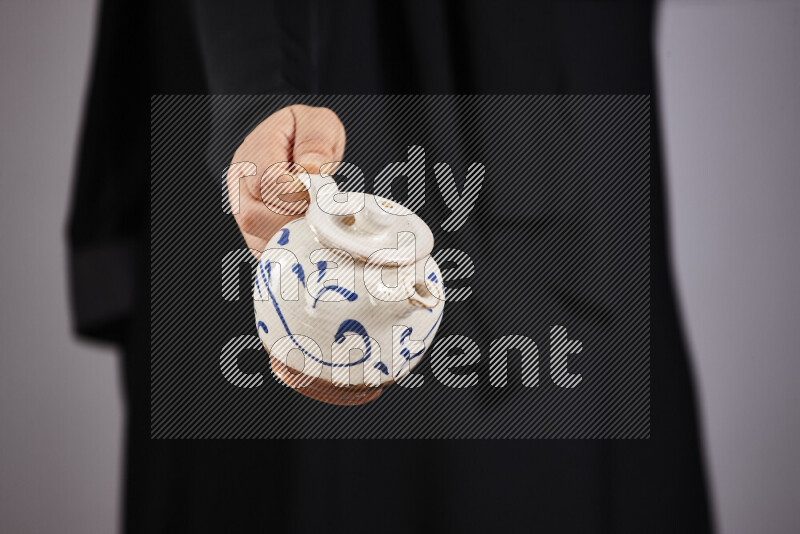 A woman in black abaya holding different pottery essentials in different positions