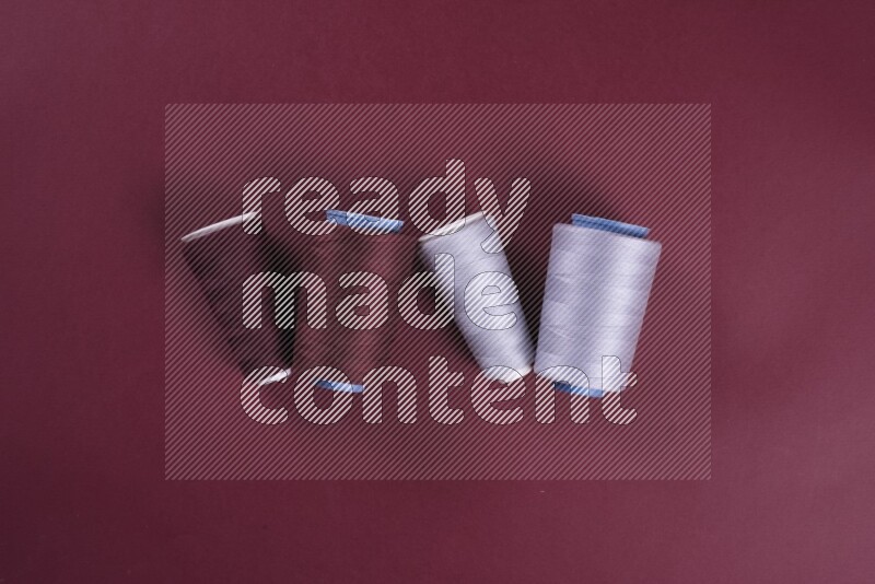 مجموعة من أدوات الخياطة والتفصيل رمادية اللون على خلفية حمراء