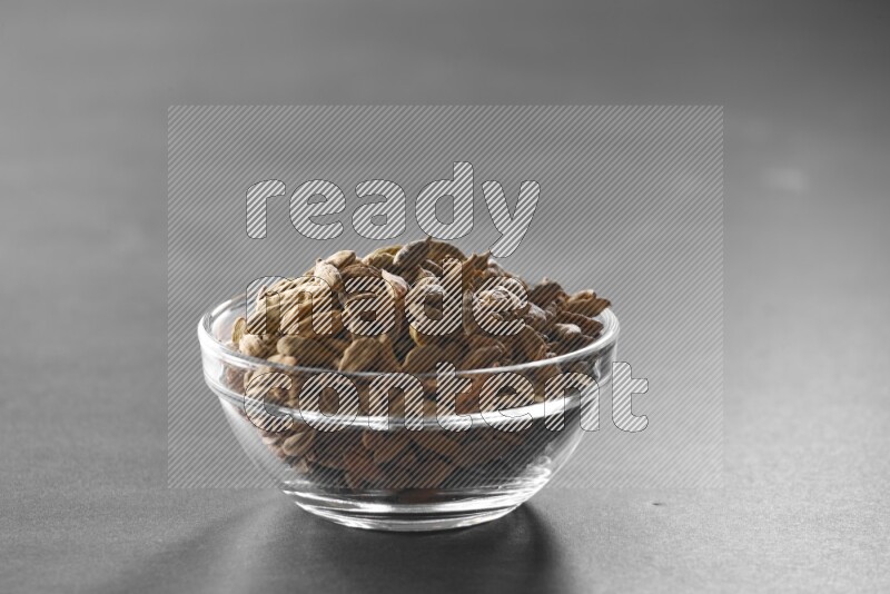 A glass bowl full of cardamom on black flooring
