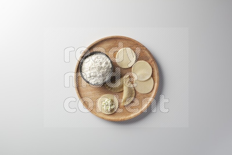 two closed sambosas and one open sambosa filled with cheese while flour aside in a wooden dish on a white background