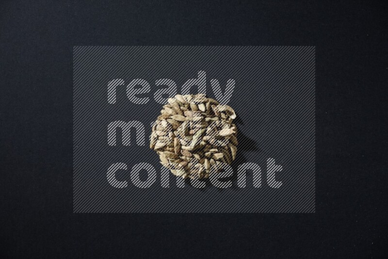 Cardamom in a circle shape on black flooring