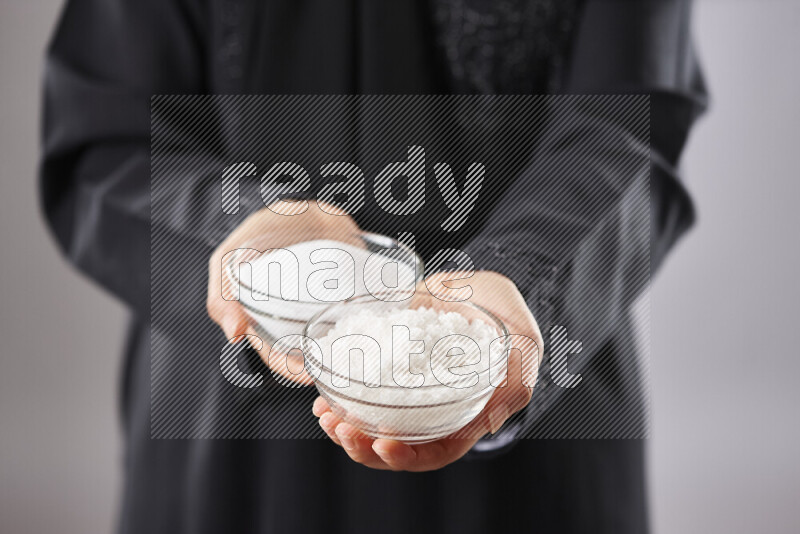 Woman in abaya holding different kinds of spices in different positions
