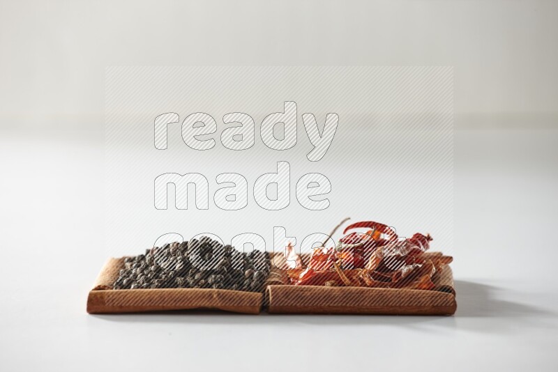 2 squares of cinnamon sticks full of red dried chilis and black pepper on white flooring