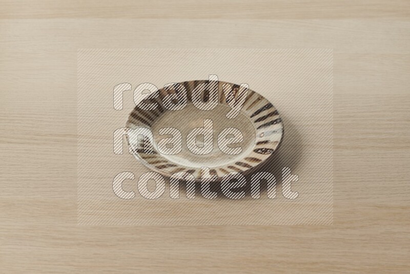 A multicolored pottery plate on light wooden background
