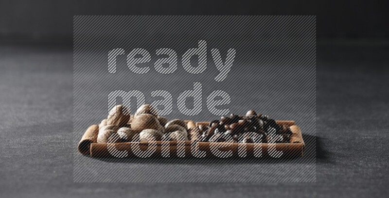 مربعان من أعواد القرفة ممتلئان بحبوب القهوة وجوزة الطيب علي خلفية سوداء