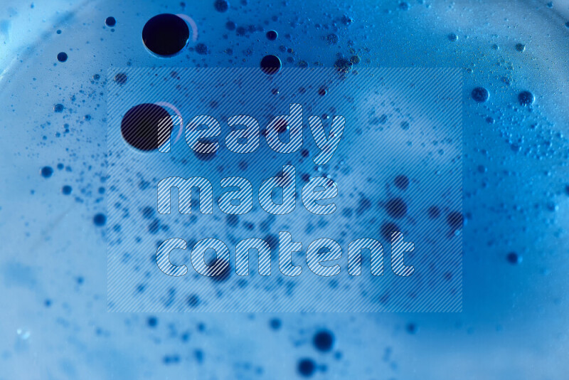 Close-ups of abstract blue watercolor drops on oil Surface on blue background
