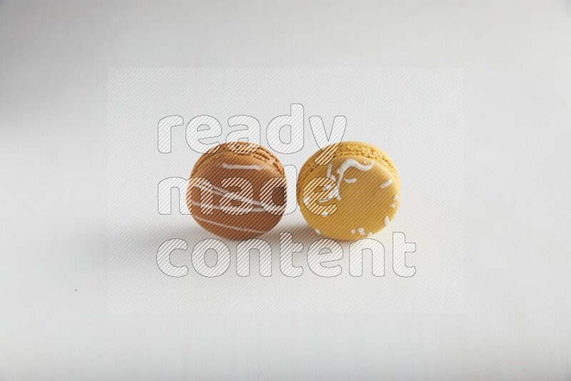 45º Shot of of two assorted Brown Irish Cream, and Yellow Piña Colada macarons on white background