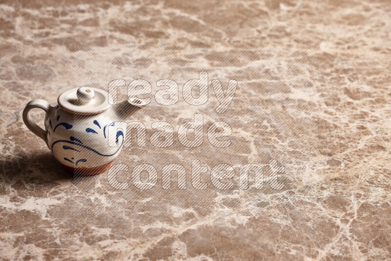 A pottery teapot on beige marble background