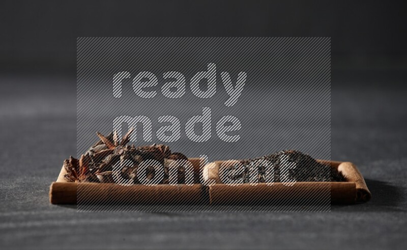 2 squares of cinnamon sticks full of star anise and black tea on black flooring