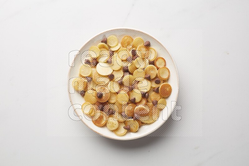Top-view shot of chocolate chips cereal pancakes in a round bowl on white background