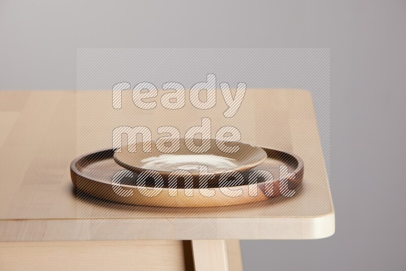 multi-colored pottery Plate placed on a light colored wooden tray on the edge of wooden table