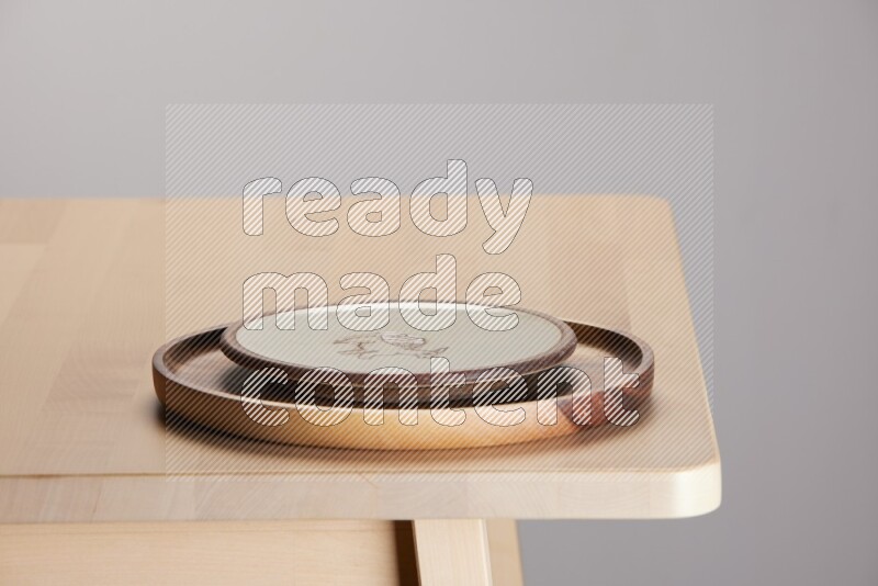 multi-colored pottery Plate placed on a light colored wooden tray on the edge of wooden table