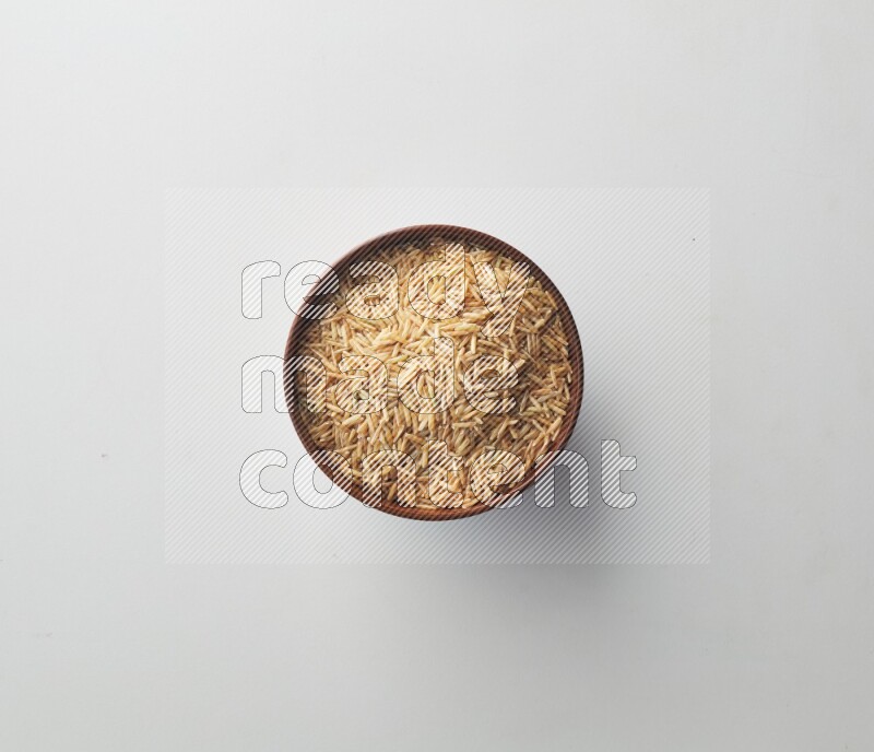 Top-view shot of long grain brown rice in a container on white background