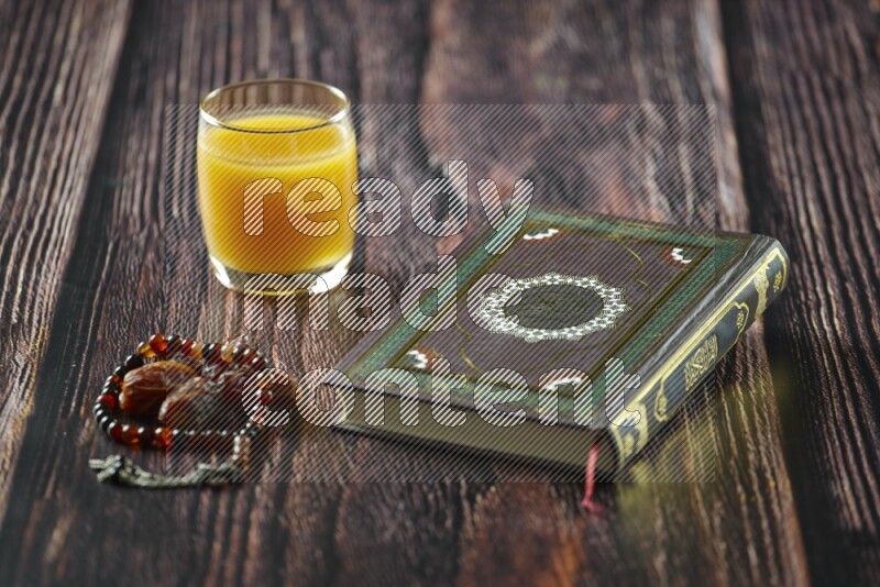 Quran with dates, prayer beads and different drinks all placed on wooden background