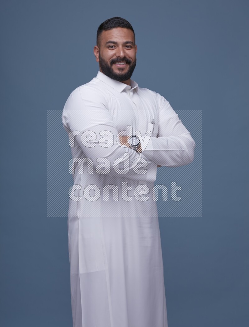 A man Posing in Blue Background wearing a Saudi Thob