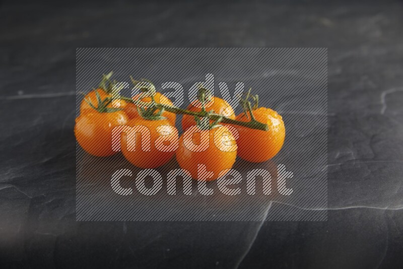 Orange cherry tomato vein on a textured black slate background 45 degree
