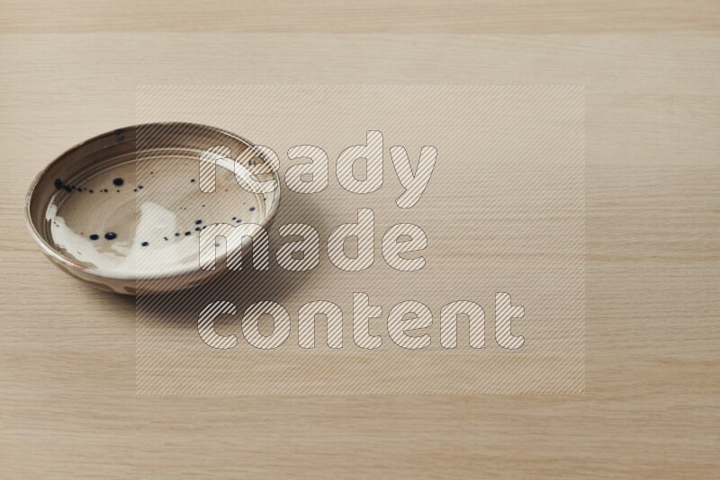 A multicolored pottery plate on light wooden background