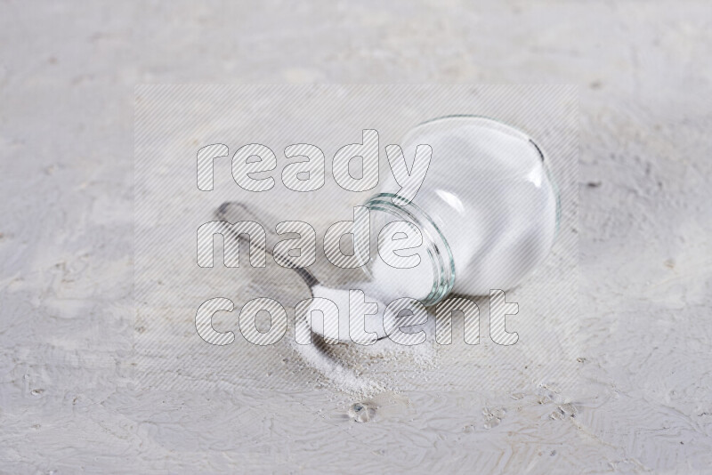 A glass jar full of fine table salt on white background